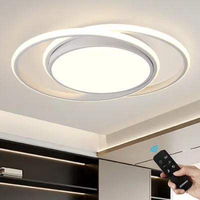 A hand holding a remote control points it towards a modern LED ceiling light fixture.