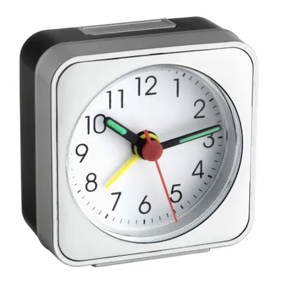 A close-up studio shot of a silver and white analog alarm clock against a white background.