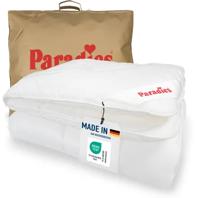 A folded white duvet is presented in front of a brown branded bag. A tag is attached to the duvet.