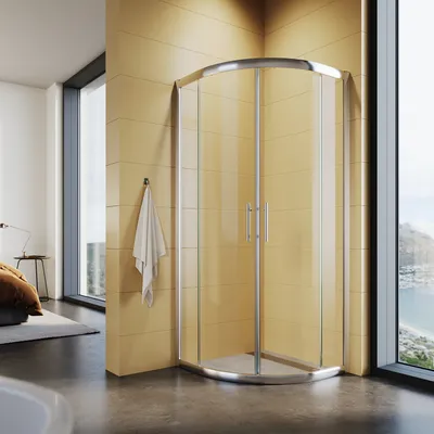 A modern bathroom with a corner shower enclosure, large windows overlooking a coastal landscape, and a bed in the background.