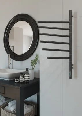 A modern bathroom scene with a sink, mirror, and a black electric towel warmer.
