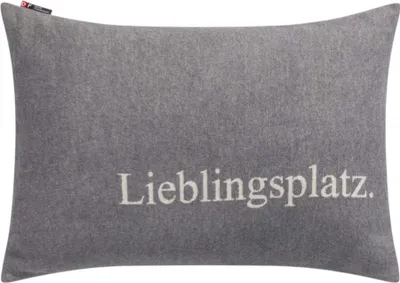 A gray pillow with the word "Lieblingsplatz" embroidered on it.
