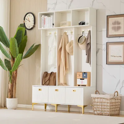 A white entryway storage set with a bench, shelves, and hooks, decorated with a plant, clock, and artwork.