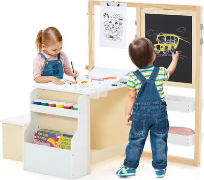 Two young children are actively engaged with a wooden easel and art station, one drawing on paper and the other on a chalkboard.