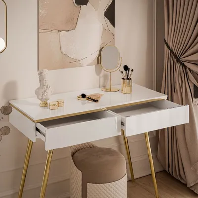 A white vanity table with gold legs and open drawers, decorated with a bust, makeup brushes, and a mirror. A stool is placed in front of the table.