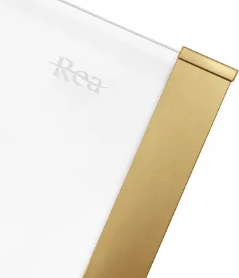 A close-up view of a shower enclosure corner with a gold-colored metal frame and a white glass panel. The brand name 'Rea' is subtly visible on the glass.