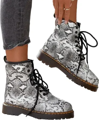 A person is wearing a pair of snake-print ankle boots.