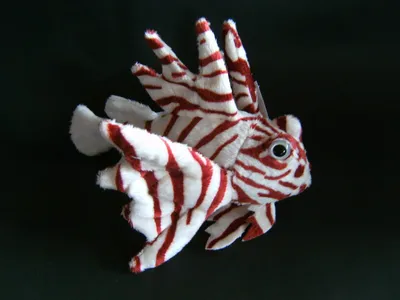 A plush toy of a lionfish against a black background.