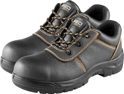 A pair of black work boots with orange stitching and laces, shown from a slightly elevated diagonal angle against a white background.