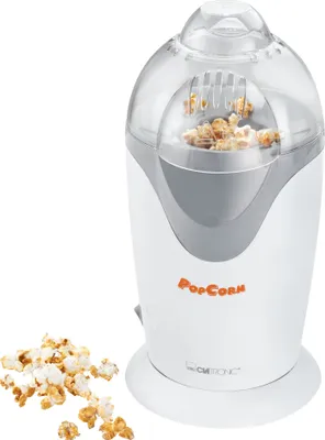 A white and gray popcorn machine with popcorn spilling out onto a white surface.