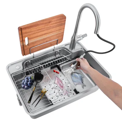 A person is using a pull-out faucet to rinse food in a stainless steel kitchen sink.