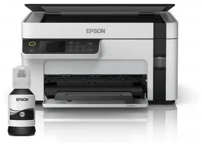 A white and black Epson EcoTank M2120 printer with a bottle of black ink in front of it, on a white background.