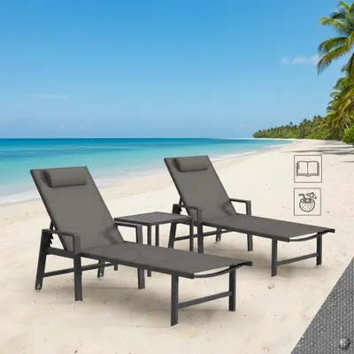 Two lounge chairs and a small table are set up on a sandy beach next to the ocean.