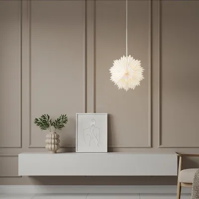 A white paper star lantern hangs above a console table with a framed artwork and a vase with greenery.