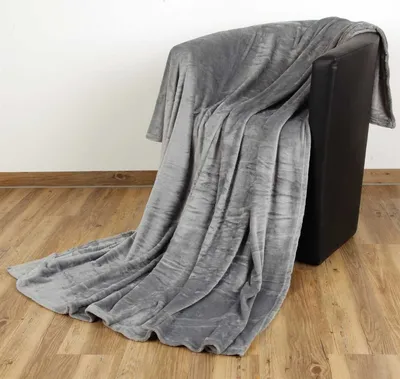 A gray blanket draped over a black armchair, with a wooden floor and white wall in the background.