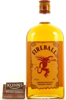 A bottle of Fireball Whisky with its cap removed, next to a small wooden sign.