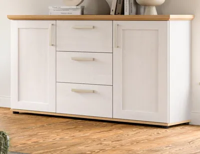 A white sideboard with wooden accents is shown in a room with wooden flooring.