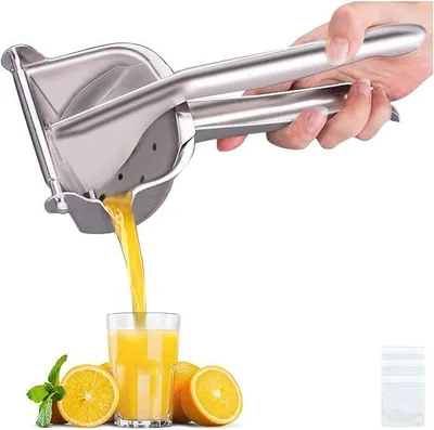 A hand is using a stainless steel citrus juicer to squeeze juice into a glass, with oranges and mint leaves around the glass.