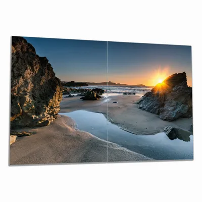 Produktbild von Wallario Herdabdeckplatte aus Glas, Größe 80 x 52 cm 2-teilig, Motiv Sonnenuntergang hinter einem Felsen am Strand