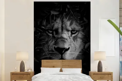 Produktbild von MuchoWow® Fototapete für Wohnzimmer oder Schlafzimmer Wandtapete Vinyl Motivtapete Nahaufnahme eines Löwen mit Blättern im Dschungel - schwarz und weiß - 195x300 cm - Das Hintergrundbild