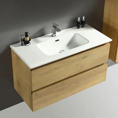 A modern bathroom vanity with a white sink and wooden drawers against a gray wall.