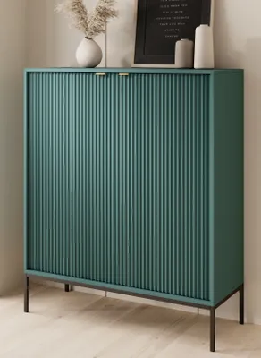 A green cabinet with gold handles sits on a black frame, with decorative items on top.