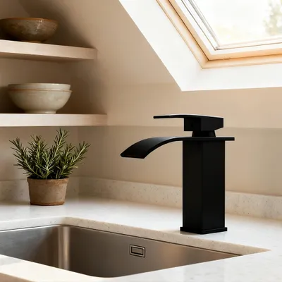 A black waterfall faucet is shown on a kitchen counter next to a sink and a potted plant.