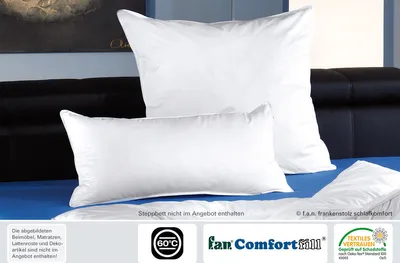 Two white pillows are displayed on a blue surface, with a dark headboard in the background.