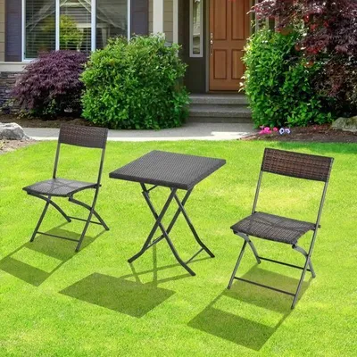 A bistro set with two chairs and a table on a green lawn in front of a house.