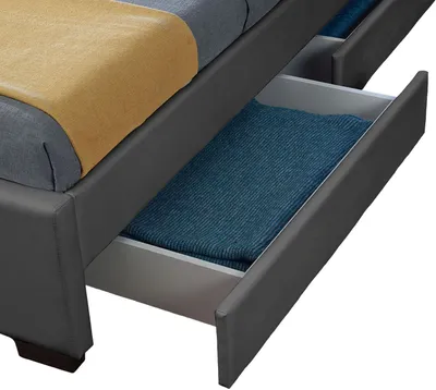 A close-up view of a bed frame with open drawers, revealing folded blankets inside.