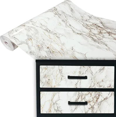 A roll of marble-patterned adhesive film is shown partially unrolled over a black cabinet with two drawers, also covered in the same marble pattern.