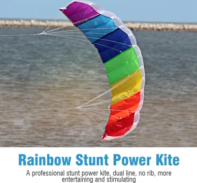 A rainbow-colored stunt kite flying over water with a stone barrier in the background.
