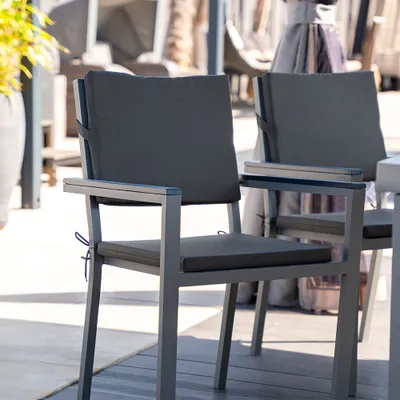 Two outdoor chairs with dark gray cushions are shown on a wooden deck.