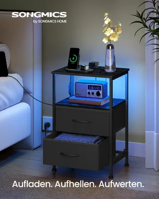 A SONGMICS BELLAH Collection nightstand with a phone charging, a radio, and decorative flowers, illuminated by blue LED lights.