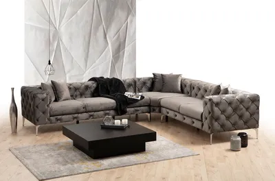A sectional sofa with a coffee table and rug in a studio setting.