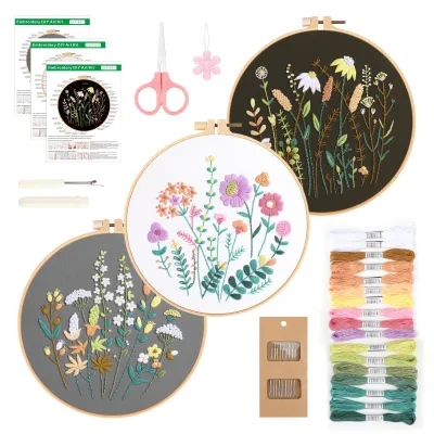 A collection of embroidery kits with floral patterns, including hoops, threads, needles, and instructions.