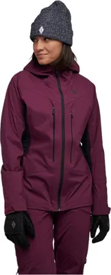 Dame in lila Hardshelljacke von Black Diamond; kombiniert mit Handschuhen und Mütze; steht vor schwarzem Hintergrund.