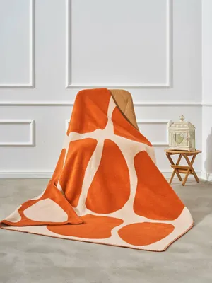 A blanket with a giraffe pattern is draped over a chair in a room with white paneled walls.