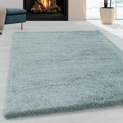 A light blue shaggy rug is placed on a light wooden floor in front of a fireplace.