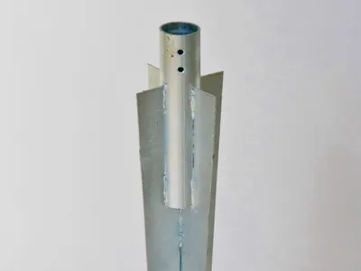 A close-up shot of a metal ground sleeve for a fence post.