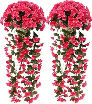 Zwei künstliche leuchtend rosa hängende Blumenarrangements mit grünen Blättern vor weißem Hintergrund