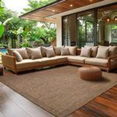An outdoor living space with a sectional sofa and a rug.