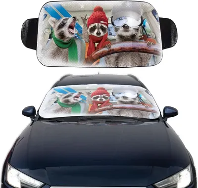 A car sunshade with a printed image of three raccoons in winter clothing driving a car is shown placed on a car's windshield.