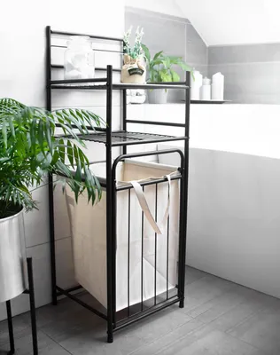 A black metal shelving unit with a laundry basket in a bathroom.