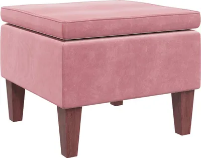 A pink velvet ottoman with wooden legs is shown against a white background.