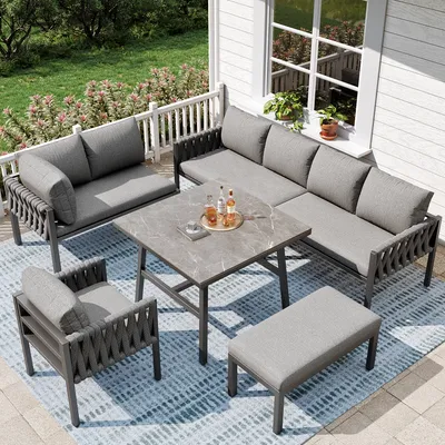 A patio set on a deck with a white railing and green grass in the background.