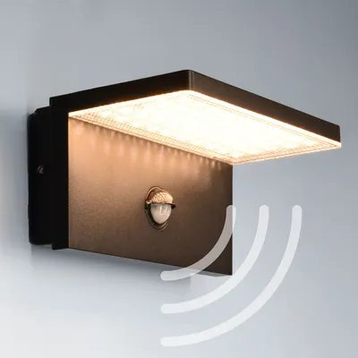 A black LED outdoor wall light with a motion sensor is mounted on a light gray wall.