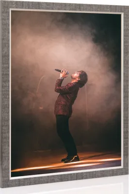 A framed picture of a singer performing on stage with smoke and spotlights.
