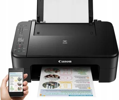 A black Canon Pixma TS3350 printer is shown with a printed document emerging from the output tray. A hand holds a smartphone displaying what appears to be a printer interface or app, suggesting wireless connectivity and control.