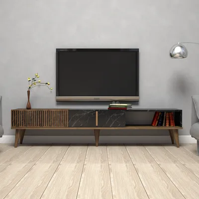 A modern TV stand with a television on top, set against a light gray wall and a light wood floor.